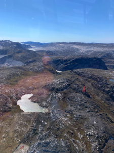 Aerial view of rocky Arctic hills, small lakes and a rust-coloured band of ground