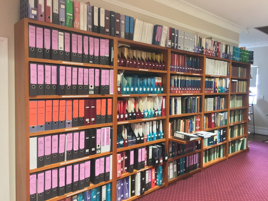 Floor-to-ceiling shelves of mining and oil-and-gas title files in a Perth office